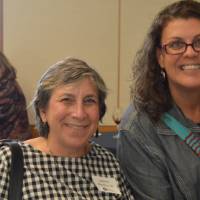Two alumnae posing for a photo with glasses of wine